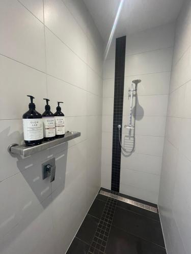 坎布里奇Titoki Grove的带淋浴和两瓶酒精饮品的浴室