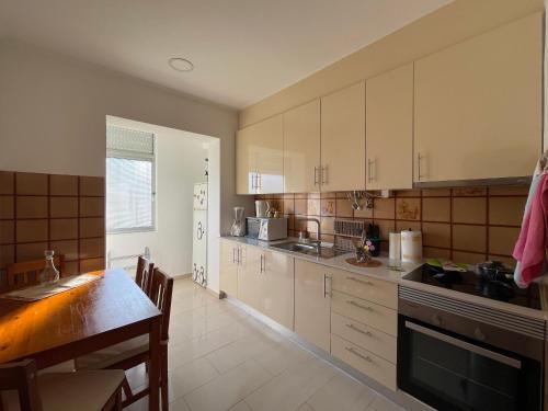 巴雷鲁Guest House “Casa da avó Tina”的厨房配有白色橱柜和桌子