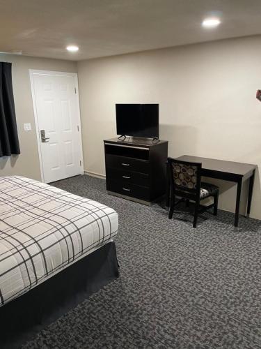 尤金Royal Inn Eugene- Airport的酒店客房配有一张床、一张书桌和一台电视。
