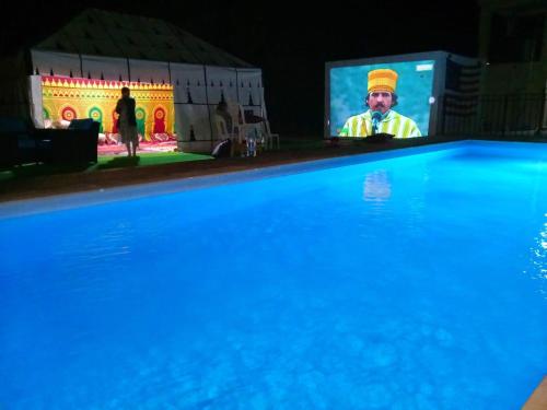 American Farm Villa Grand Casablanca/El Jadida的游泳池旁屏幕上的男人