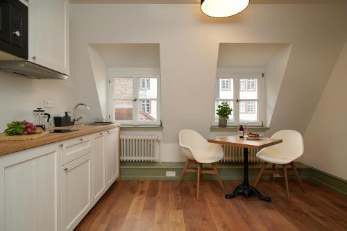 海德堡Palmbräu Altstadt Appartments的厨房配有白色的椅子和桌子以及2扇窗户。