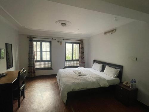 加德满都Hotel Little Buddha Inn的一间卧室配有一张床、一张书桌和两个窗户。