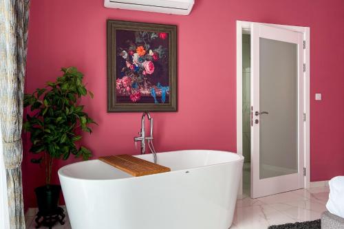 拉巴特100 Boutique Living的带浴缸的浴室和粉红色的墙壁