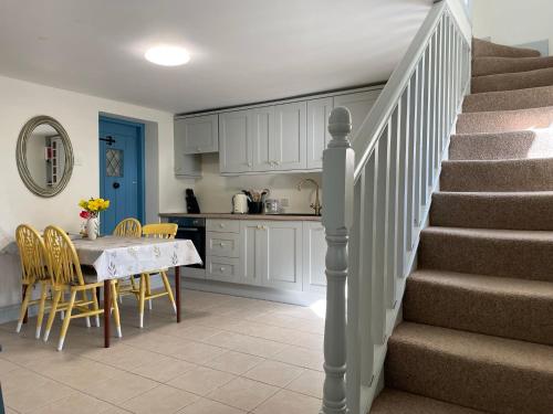 基尔马勒克Mai's Cottage Suite - Charming Holiday Rental的厨房以及带桌子和楼梯的用餐室。