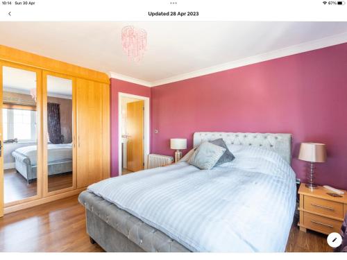 科尔温湾The Kings Suite Oak Drive, Colwyn Bay LL29 7YP FIRST FLOOR的一间卧室配有一张床和粉红色的墙壁