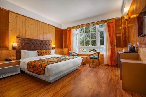 拉亨Summit Gangchen Hotel的一间卧室配有一张床、一张书桌和一个窗户。