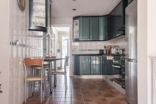 雷阿尔城Unifamiliar Europa的厨房配有绿色橱柜和酒吧凳子