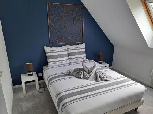 拉尼翁Appartements Lannion proche centre, Côtes de Granit Rose的蓝色卧室,配有一张床,床上有一个弓
