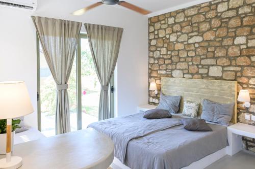 塞奥洛戈斯LOGOS Beach Village的一间卧室设有石墙和一张带枕头的床。