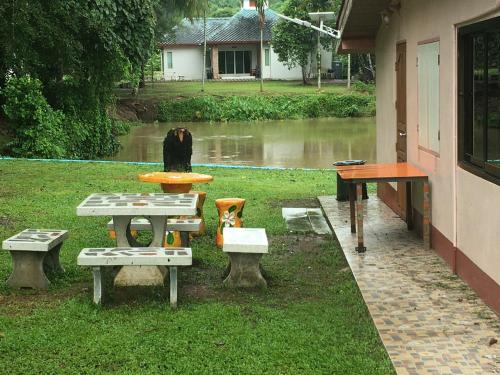 Ban Khok Sawang (2)นาหินลาดรีสอร์ท Nahinlad Resort的房屋旁的野餐桌和长凳