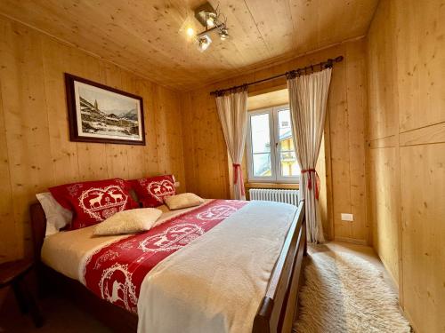 博尔米奥Chalet Ame的一间卧室配有一张铺有红白色床单的床和一扇窗户。