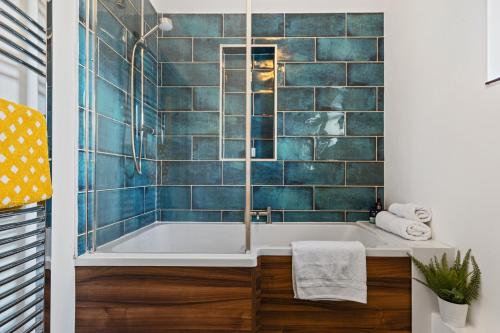 滕比Woodfield House - Beautiful Tenby Cottage的浴室设有蓝色瓷砖浴缸。