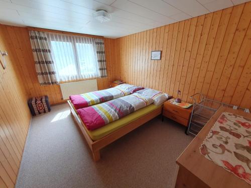 Unterschächen乌腾斯查岑假日公寓酒店的一间卧室设有一张床和木墙