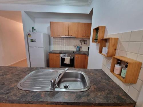 珀斯Little Monica Apartment- Spacious, Affordable & Central的厨房配有水槽和白色冰箱