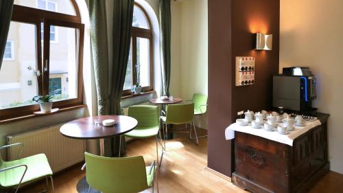 格拉茨吕克特别墅酒店的餐厅设有绿色的椅子和桌子以及窗户。