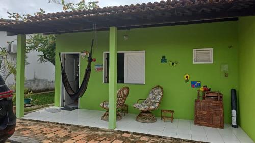 巴雷里尼亚斯Chalé 15 Porto dos Lençóis的绿色房子,带两把椅子和一扇门