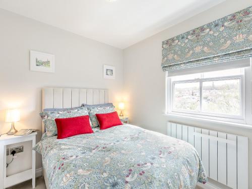 StrinesAnnes Cottage的一间卧室配有一张带红色枕头的床和一扇窗户