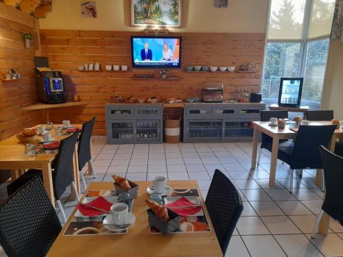 LangeacHotel de l'Ile d'Amour的一间设有桌子的用餐室和墙上的电视