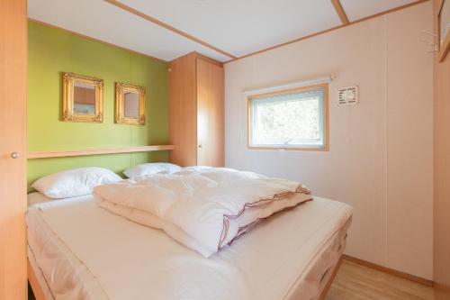 米茨兰Heidehut的一间卧室配有一张带白色床单的床和一扇窗户。