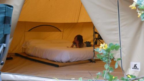 卡莱利亚德帕拉弗鲁赫尔ACAMPALE - Camping Costa Brava - Calella de Palafrugell的坐在帐篷里的床上的女人