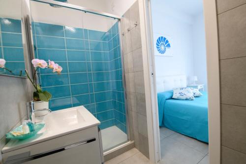 波尔图·埃尔科莱Marina House Porto Ercole的蓝色瓷砖浴室设有水槽和淋浴