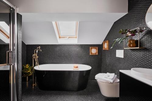 卢森堡Halcyon Days Luxembourg的黑色浴室设有浴缸和水槽