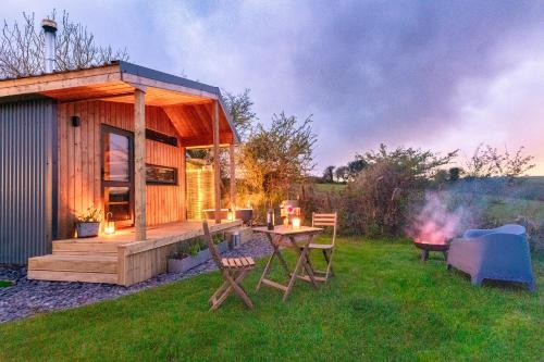 特鲁罗Luxury Glamping Cabin with Outdoor Bath on Cornish Flower Farm的小屋在草地上配有桌椅