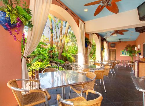 坦帕Tahitian Inn Boutique Hotel Tampa的一间设有桌椅的餐厅,种植了植物