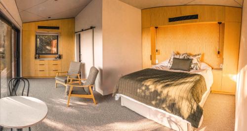 基督城Tussock Hill Vineyard Retreats的卧室配有一张床和一张桌子及椅子