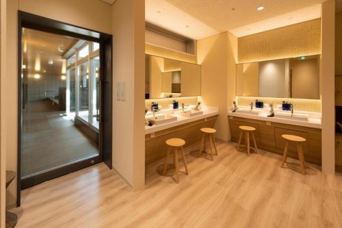 静冈HOTEL OLE INN的一间带三个水槽和两个凳子的浴室