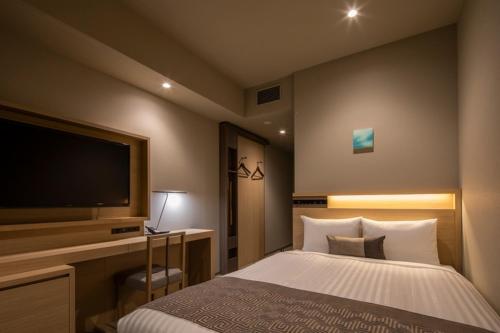 静冈HOTEL OLE INN的一间卧室配有一张床和一台平面电视