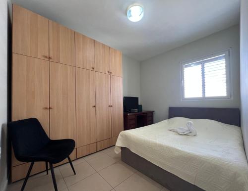 巴特亚姆ISRALUX APARTMENTS的卧室配有床、椅子和窗户。
