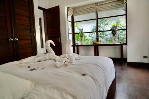 苏梅岛3 Bedroom Seaview Villa Halo on Beachfront Resort的卧室配有带鲜花的白色床