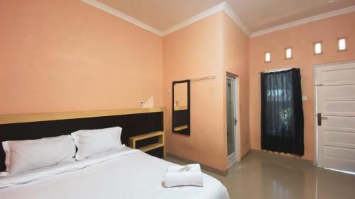DukuPenginapan Malompek Syariah的卧室设有一张白色大床和一扇窗户。
