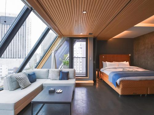 东京Asakusa Kokono Club Hotel的一间卧室配有一张床、一张沙发和窗户。