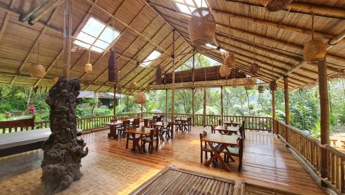 TomohonRimba eco Resort的一间铺有木地板并配有桌椅的餐厅