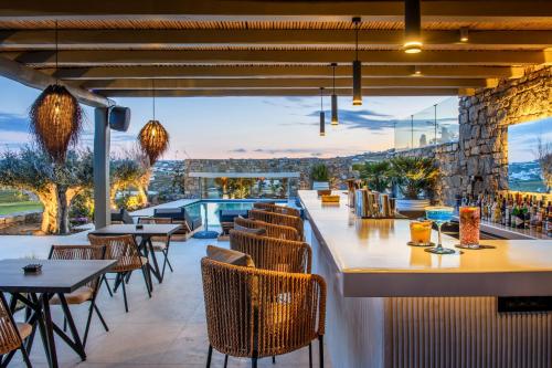 米克诺斯城Nasta Suites & Villas Intentional Living Mykonos的餐厅享有游泳池的景致,配有桌椅