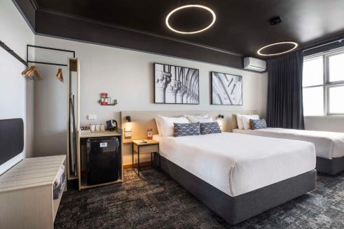 Gepps CrossNightcap at Empire Hotel的酒店客房设有两张床和电视。