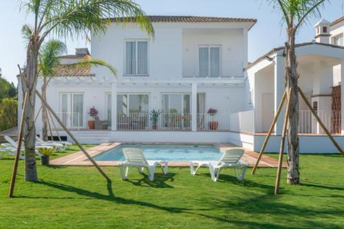 贝纳卢普-卡萨斯维耶哈斯Villa Girasol的一个带两把椅子的院子、一个游泳池和一个房子