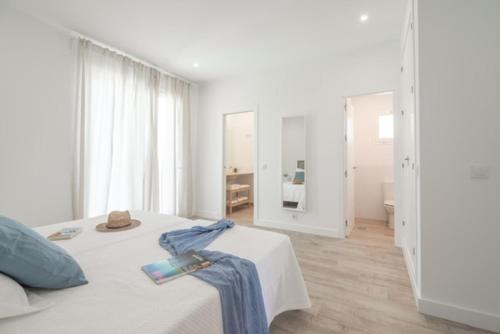 贝纳卢普-卡萨斯维耶哈斯Villa Girasol的白色卧室,配有一张带蓝色毛巾的床