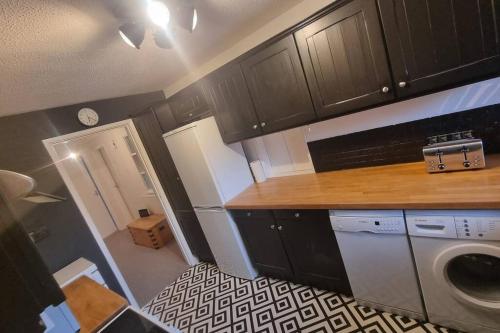 利明顿Spacious self contained flat in superb location的厨房配有黑色橱柜、洗衣机和烘干机