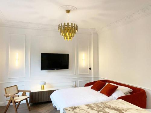 格勒诺布尔Le petit Versailles - T2 au centre-ville的一间卧室配有一张床、一台电视和吊灯。