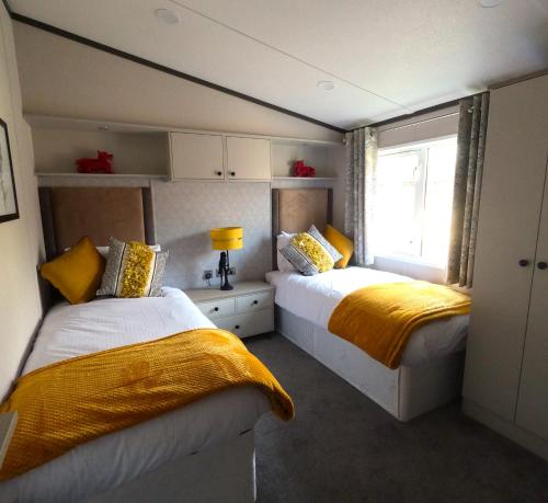 莫尔顿Macaw Lodge的一间卧室设有两张带黄床单的床和窗户。
