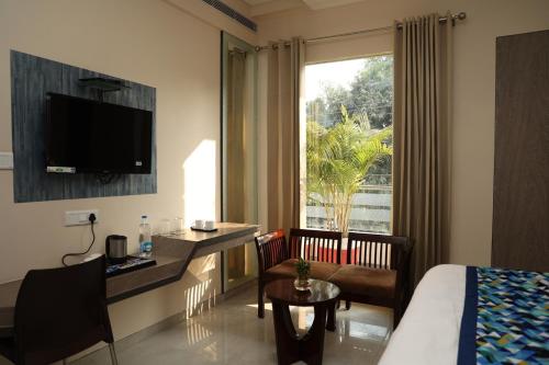 勒克瑙Hotel Pinaka Inn的配有一张床、一张书桌和一扇窗户的酒店客房