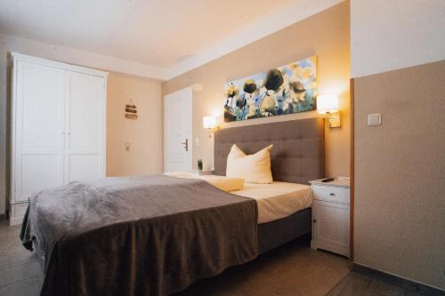 宾茨阿斯特丽德海滨旅馆的卧室配有一张床,墙上挂有绘画作品