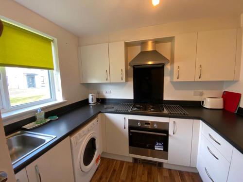 爱丁堡3 bed house with parking near airport的厨房配有水槽和炉灶 顶部烤箱