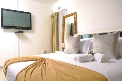 哈博罗内acaciaoptimumstay的卧室配有一张大白色床和平面电视