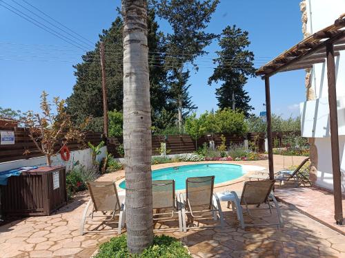 VrysoulesTraditional Villa Sofia的游泳池旁棕榈树周围的桌椅