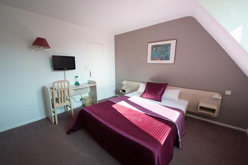 日安安妮·德博热酒店的一间卧室配有一张床和一张书桌及电视