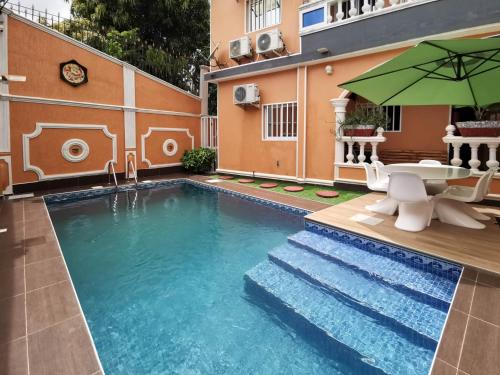 Agbata Guest House的一个带桌子和遮阳伞的游泳池